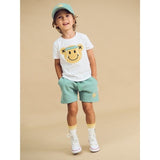 Boy wearing HUXBABY Tennis Bear Short and matching cap and tee. Studio shot.