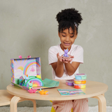 Child playing with clay unicorns on a table against a plain background