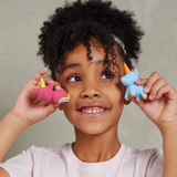 Child holding two colourful clay unicorn toys against a neutral background