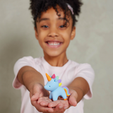 Child holding a small clay unicorn toy with a plain background