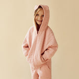 Studio shot of girl wearing the hood up on the WILSON & FRENCHY Pretty Pink Organic Quilted Jacket and matching trackpant
