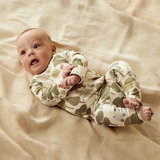 Baby lying on back on floor wearing WILSON & FRENCHY Little Trees Organic Zipsuit With Feet