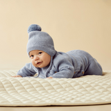 Baby lying on tummy wearing WILSON & FRENCHY Blue Speckle Organic Knitted Bonnet and matching Kimono Knit Jumper & Leggings