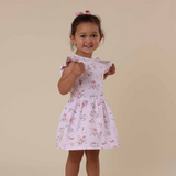 Young girl wearing a floral dress against a beige background
