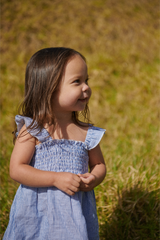 Young girl in a blue striped dress standing in a grassy field
