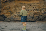 Back view of child wearing the CRYWOLF Explorer Jacket - Fern Colourblock, Tan rain overalls and Fern Rain Boots