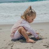 Child sitting on sand wearing CRYWOLF Baby Rash Vest - Ditsy Floral