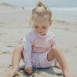Child sitting on sand wearing CRYWOLF Baby Rash Vest - Ditsy Floral