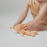 Child sitting on floor playing with OLLI ELLA Dinky Dinkum Dolls - Scottie Snail - Orange