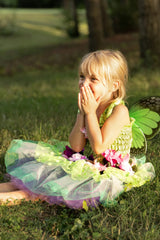 Young girl in a fairy costume sitting on grass