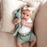 Baby holding a plush toy on a beige couch