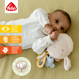 Baby playing with a soft toy, lying on a textured surface with Fehn logo above.