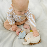 Baby playing with soft toys on a light blanket