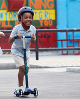 Child riding a scooter with a colorful mural in the background