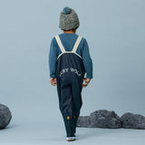 Back view of child wearing CRYWOLF Rain Overalls - Indigo and matching rain boots