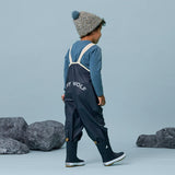 Back-Angle view of child wearing CRYWOLF Rain Overalls - Indigo and matching rainboots