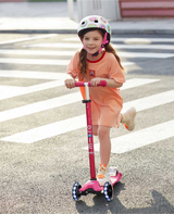 Child riding a pink scooter on a crosswalk