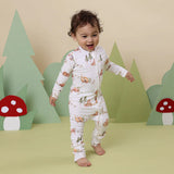 Child wearing a forest-themed onesie with a bear and tree background