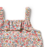 Floral patterned baby romper with ruffled straps on a white background
