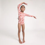 Young girl in a pink swimsuit with heart patterns on a white background