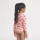 Girl wearing a strawberry-patterned swimsuit on a white background