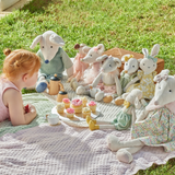 Child lying on blankets outside with a variety of stuffed toy animals