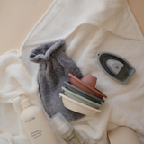 Bath products including a bottle, washcloth, and soap on a towel with a set of plastic bath boats on display.