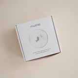 Whale muslin in Mushie product packaging on a beige background