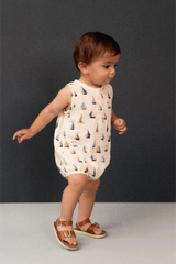 Baby wearing a sailboat-patterned romper against a dark background