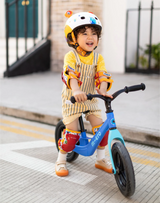 Child riding a balance bike on a sidewalk
