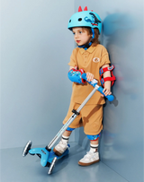 Child with a scooter wearing protective gear against a light blue wall