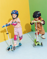 Two children on scooters against a colorful background
