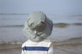 Back view of a child wearing a large sun hat on a beach