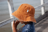 Child wearing an orange bucket hat on a beach