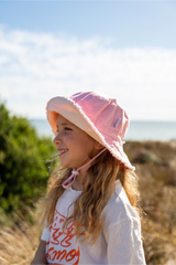 Child wearing a pink sun hat outdoors with a blurred background