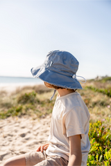Child wearing a blue sun hat on a beach