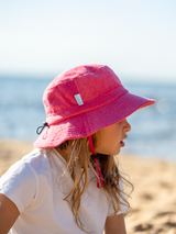 Person wearing a pink bucket hat on a beach