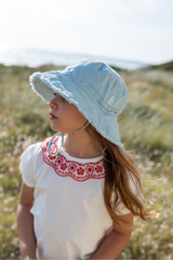 Child wearing a light blue sun hat in a natural setting