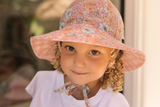 Young girl wearing a floral sun hat with a blurred background