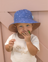 Child wearing a blue hat with fishing theme print, eating watermelon
