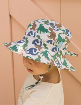 Top angle view of child wearing a dinosaur hat with blue, green and brown t-rex dinos all over it