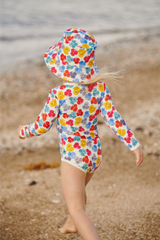 Child wearing a colourful floral swimsuit and matching bucket hat on a beach