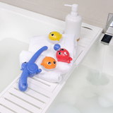 Colorful bath toys and a bottle on a white bathtub tray.