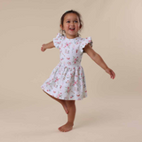 Child wearing a floral dress on a beige background