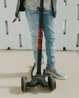 Person standing on a Micro scooter with a white wall background