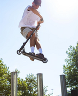Person riding a scooter in an outdoor setting with trees in the background
