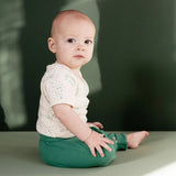 Baby sitting on a green surface with a blurred green background