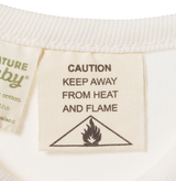 Textile label with 'Caution: Keep Away from Heat and Flame' warning on a white background