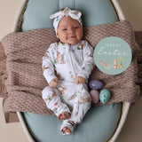 Baby lying in bassinet wearing SNUGGLE HUNNY Easter Bunnies Organic Snugglesuit Convertible Romper and matching headband