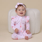 Baby sitting on floor wearing SNUGGLE HUNNY Coral Organic Snugglesuit Convertible Romper with Frill